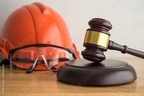 Hammer judge gavel with construction hat helmet, worker safety glasses on wooden background. Labour law concept. Wages, overtime pay, welfare, occupational safety, health, environment, severance pay. photo