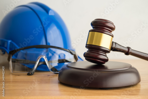 Hammer judge gavel with construction hat helmet, worker safety glasses on wooden background. Labour law concept. Wages, overtime pay, welfare, occupational safety, health, environment, severance pay. photo