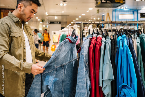 Crop ethnic man choosing clothes in shop