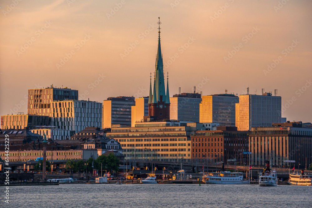 Obraz premium Stockholm, Sweden. Old church spiral surrounded by new buildings in the orange sunset
