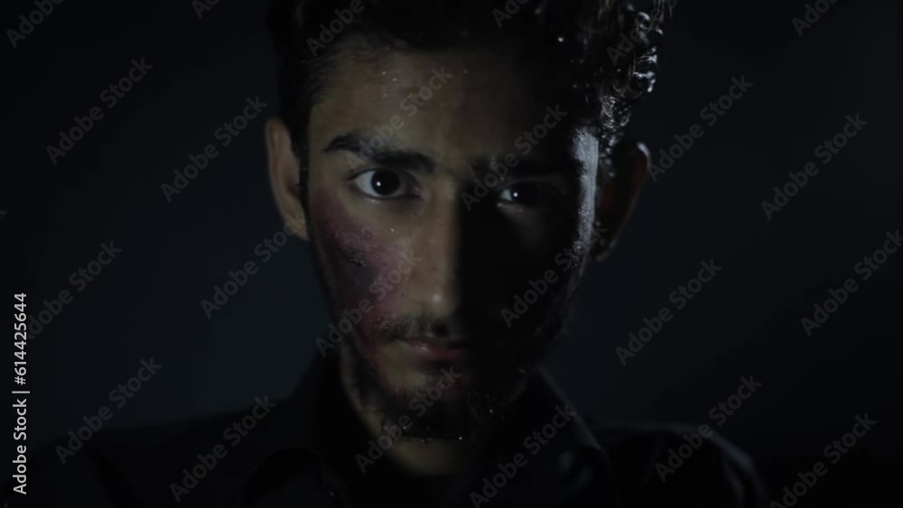 Low angle shot of an injured with minor blood on his face coming closer to the camera in a dark mysterious room, Hd footage. Low angle shot of an injured with minor blood on his face coming closer to the camera in a dark mysterious room, Hd footage.