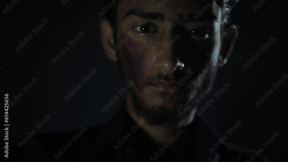 Low angle shot of an injured with minor blood on his face coming closer to the camera in a dark mysterious room, Hd footage. Low angle shot of an injured with minor blood on his face coming closer to the camera in a dark mysterious room, Hd footage.