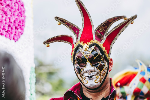 Homme qui porte un masque de carnaval coloré rouge noir blanc doré