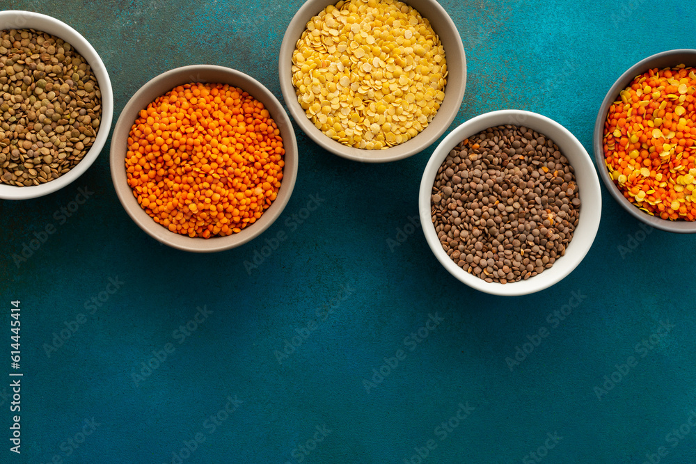 Multicolored lentils in bowls on an emerald green background, yellow and brown, green and orange lentils, healthy legumes, top view, copy space Multicolored lentils in bowls on an emerald green background, yellow and brown, green and orange lentils, healthy legumes, top view, copy space