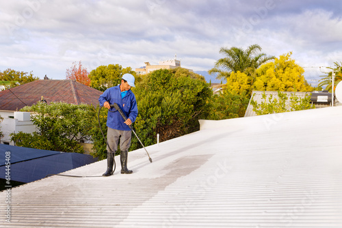 A man doing high pressure spray cleaning of a roof in preparation of painting, in Worcester, Western Cape, South Africa.