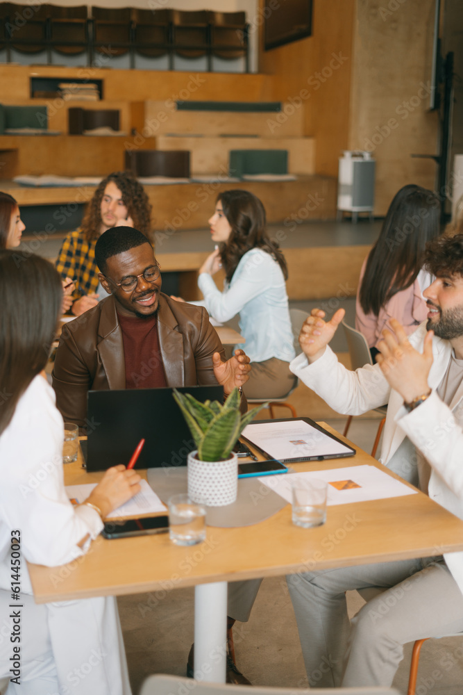 Fototapeta premium Young, multiracial coworkers discussing profit growth together at modern co working space