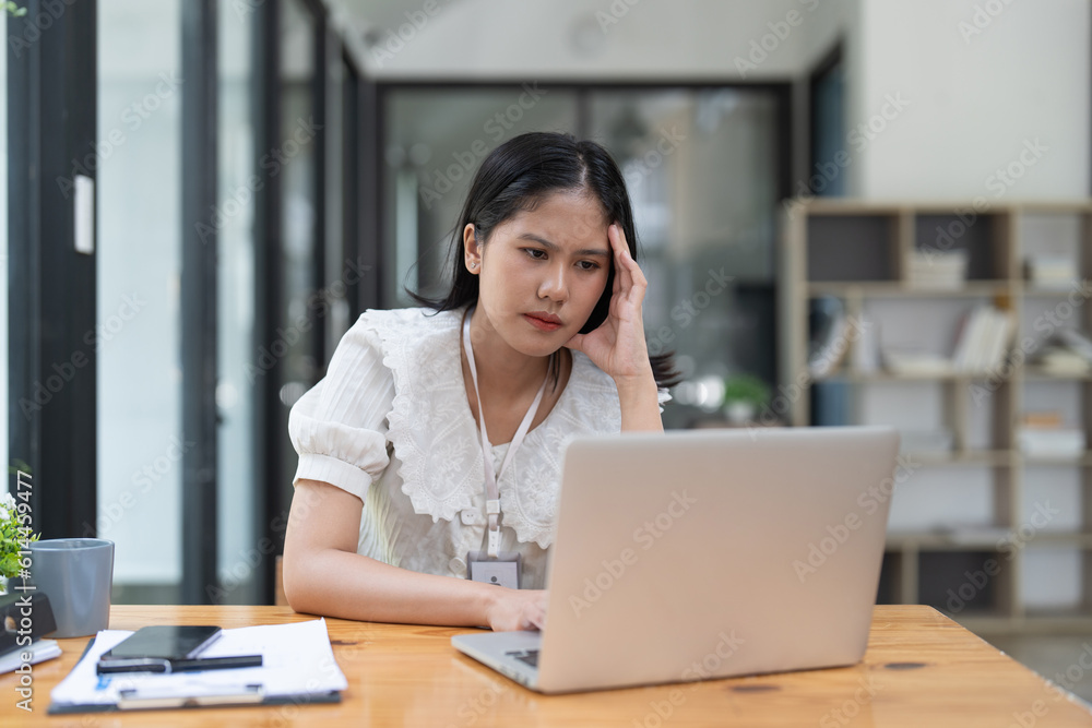 Stressed Financier a asian woman at works, uses a laptop, makes a report to a finance company. Accounting and financial concept Stressed Financier a asian woman at works, uses a laptop, makes a report to a finance company. Accounting and financial concept