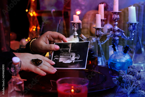 spiritualistic seance in salon of medium with old photographs of deceased relatives, Female Fortuneteller or esoteric Oracle, longing for ancestors, communication with world spirits, help of ancestors photo