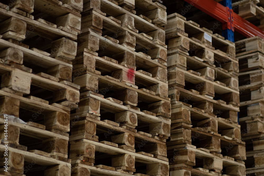 a large pile of wood, stacks of pallets in warehouse