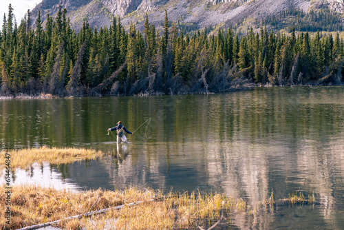 Fly fishing on a lake surrounded by pine trees on the edge of a mountain, Pine Lake, Haines Junction, Yukon, Canada