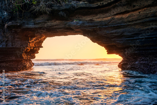 Natural rock cave formation and wave in the sunset