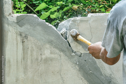 Hand of worker using hammer smashing and demolish on brick wall at construction site
