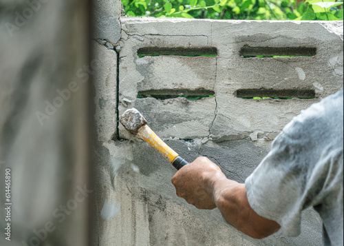 Hand of worker using hammer smashing and demolish on brick wall at construction site