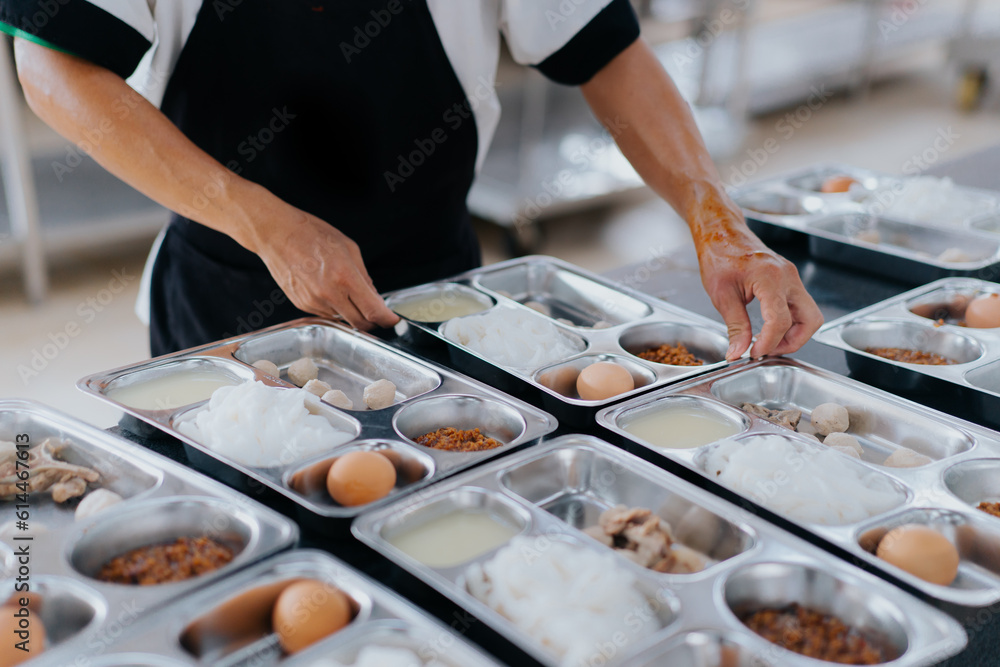 chef preparing food into a tray of food