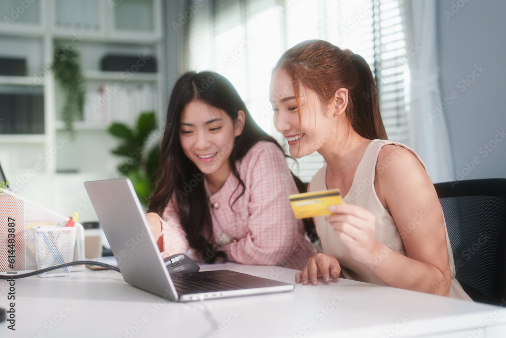 Young girls looking into computer doing online shopping holding credit card to pay, using electronic banking, e-commerce, social buying feeling happy and enjoy with online store. Young girls looking into computer doing online shopping holding credit card to pay, using electronic banking, e-commerce, social buying feeling happy and enjoy with online store.