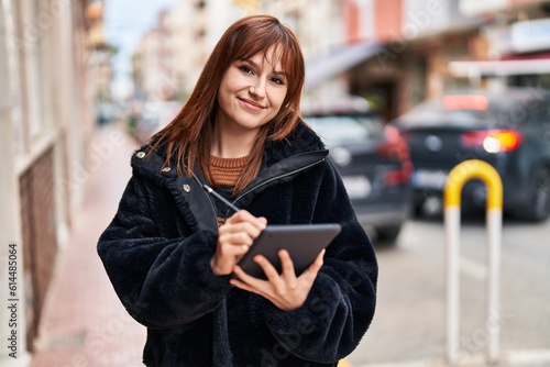 Young woman smiling confident using touchpad at street