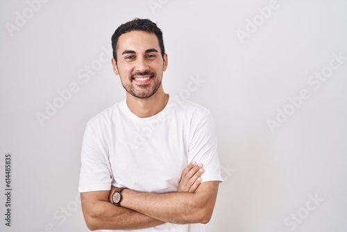 Murais de parede Handsome hispanic man standing over white background happy face smiling with crossed arms looking at the camera