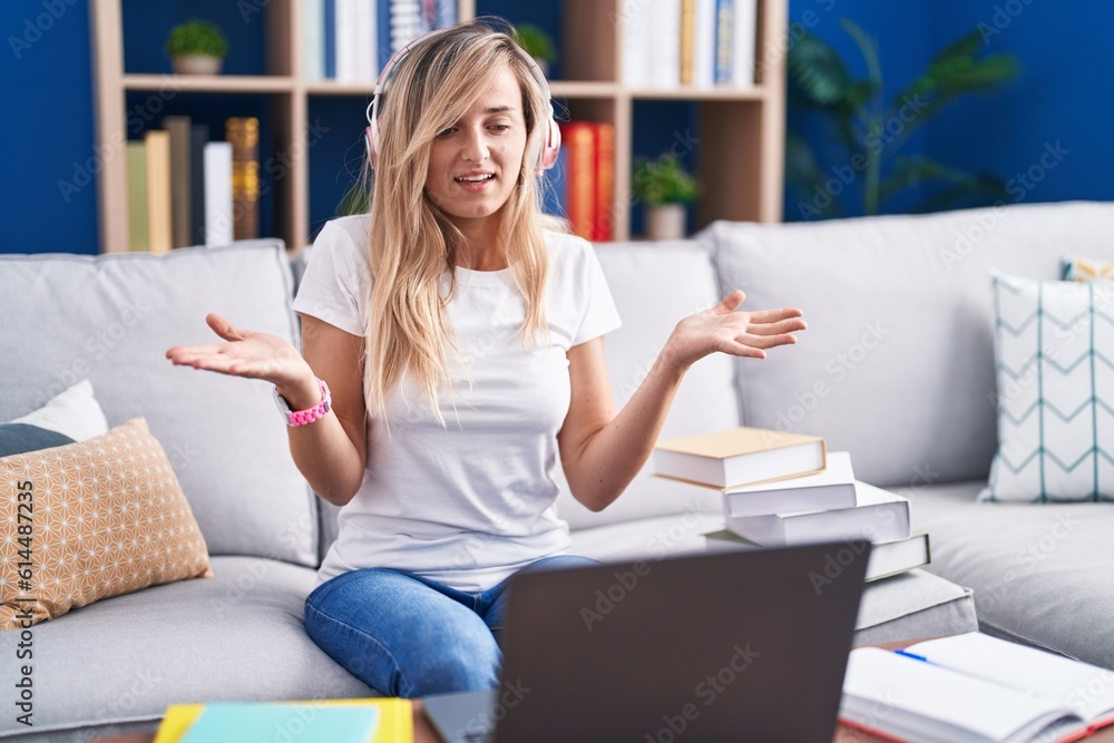 Obraz premium Young blonde woman studying using computer laptop at home smiling cheerful offering hands giving assistance and acceptance.
