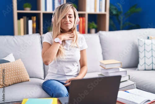 Young blonde woman studying using computer laptop at home cutting throat with hand as knife, threaten aggression with furious violence