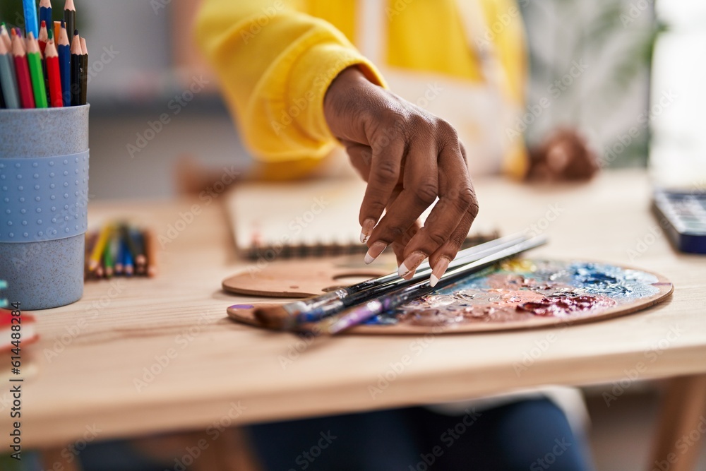 African american woman artist holding paintbrush at art studio