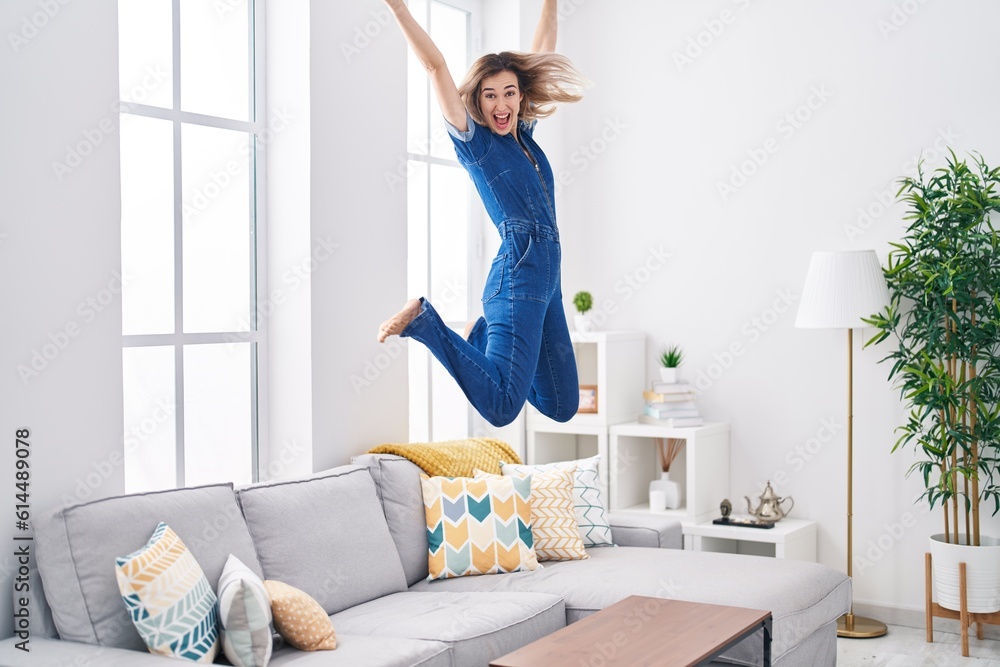 Young woman smiling confident jumping on sofa at home Young woman smiling confident jumping on sofa at home