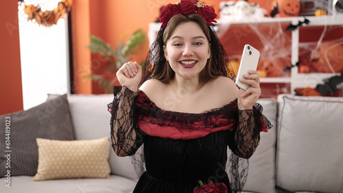 Young blonde woman wearing katrina costume using smartphone at home photo