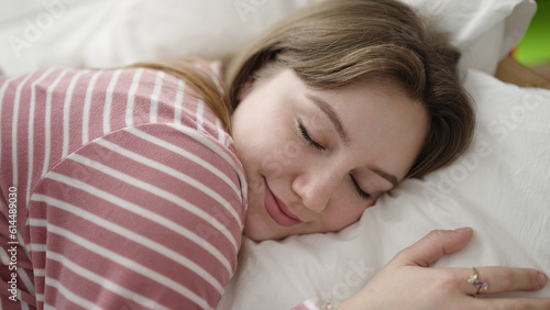 Young blonde woman lying on bed sleeping at bedroom