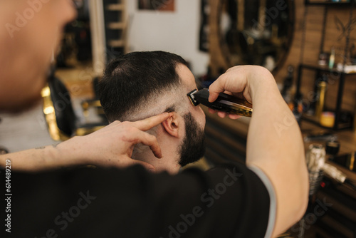Side view of Professional barber cutting hair of his client. 