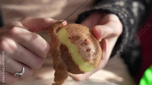 Close up of women holding and peeling potato with a knife