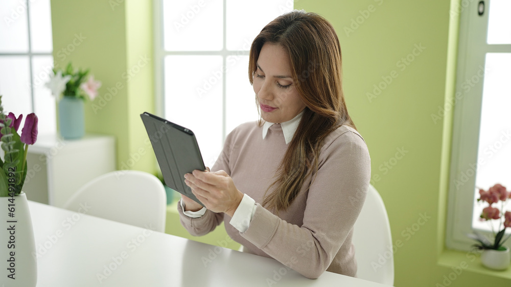 Young beautiful hispanic woman using touchpad sitting on table at home Young beautiful hispanic woman using touchpad sitting on table at home