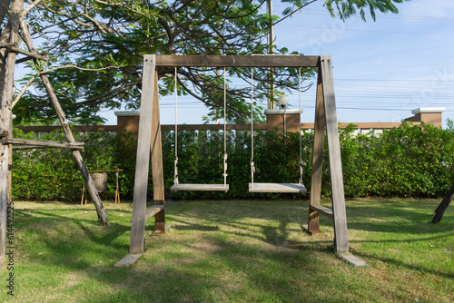 Wooden swing on the green grass in the garden, Thailand.