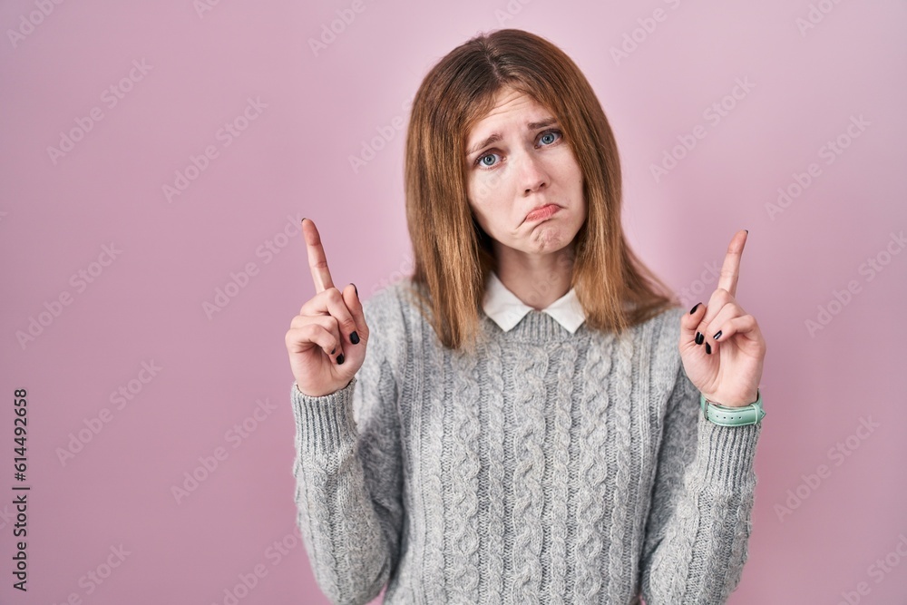 Beautiful woman standing over pink background pointing up looking sad and upset, indicating direction with fingers, unhappy and depressed. Beautiful woman standing over pink background pointing up looking sad and upset, indicating direction with fingers, unhappy and depressed.