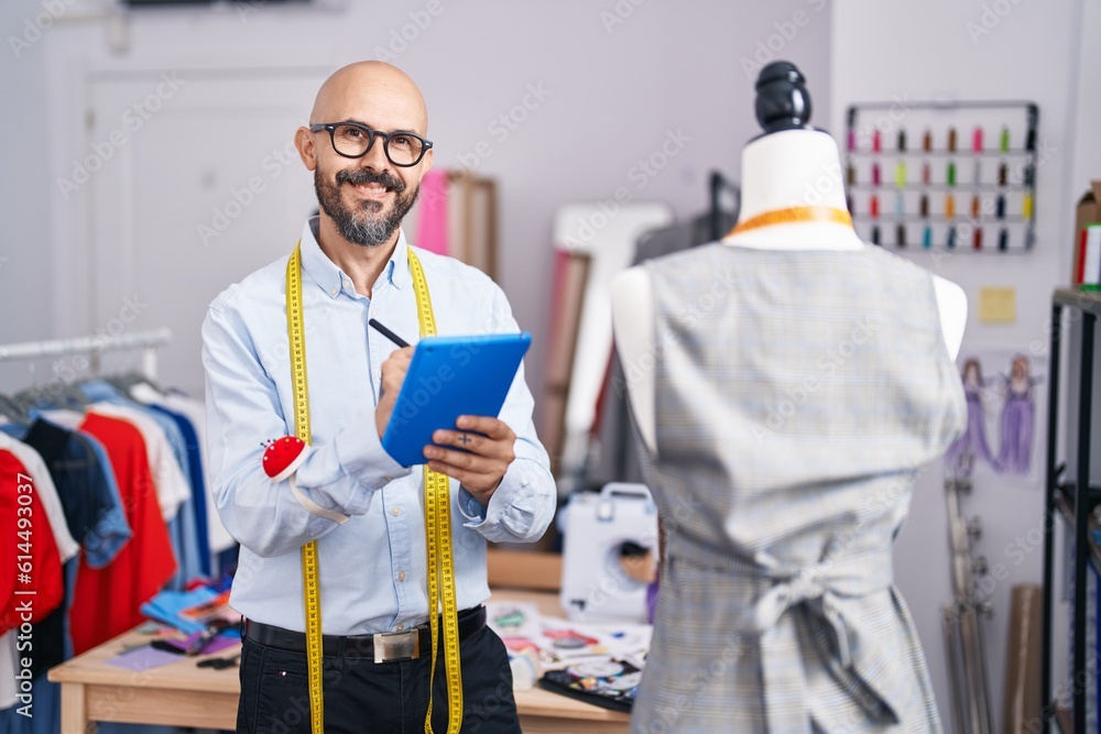 Young bald man tailor smiling confident drawing on touchpad at tailor shop Young bald man tailor smiling confident drawing on touchpad at tailor shop