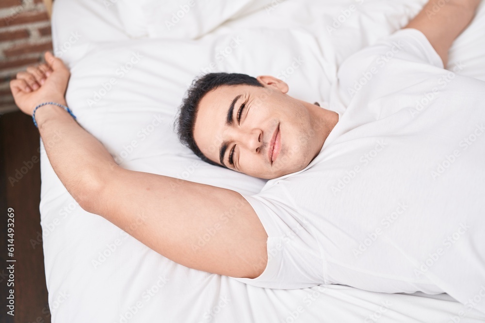 Young hispanic man waking up stretching arms at bedroom Young hispanic man waking up stretching arms at bedroom