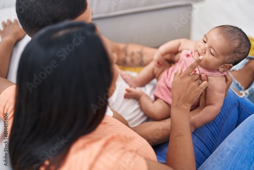 Hispanic family hugging each other sitting on sofa at home