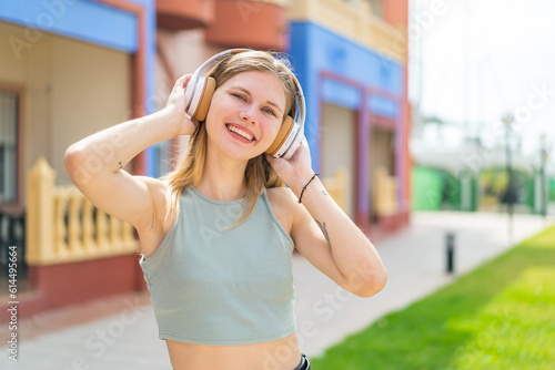 Young blonde woman at outdoors listening music