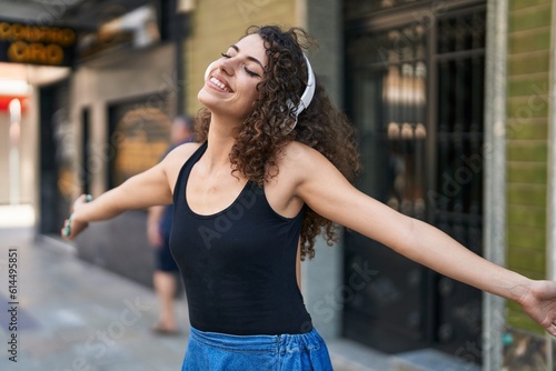 Young beautiful hispanic woman listening to music and dancing at street