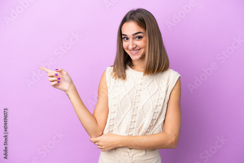 Young caucasian woman isolated on purple background pointing finger to the side © luismolinero