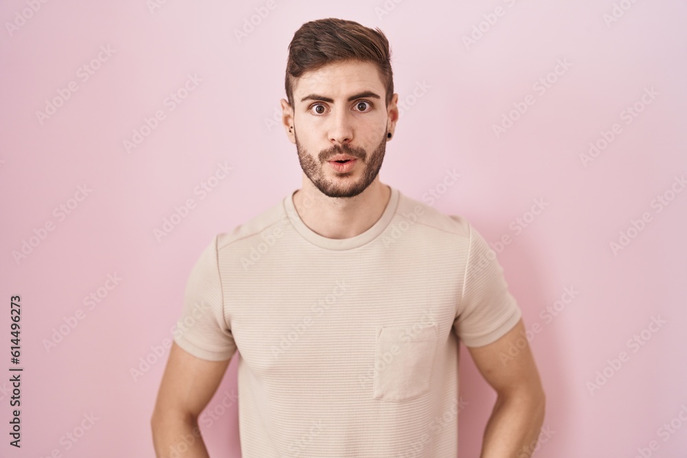 Fototapeta premium Hispanic man with beard standing over pink background afraid and shocked with surprise and amazed expression, fear and excited face.
