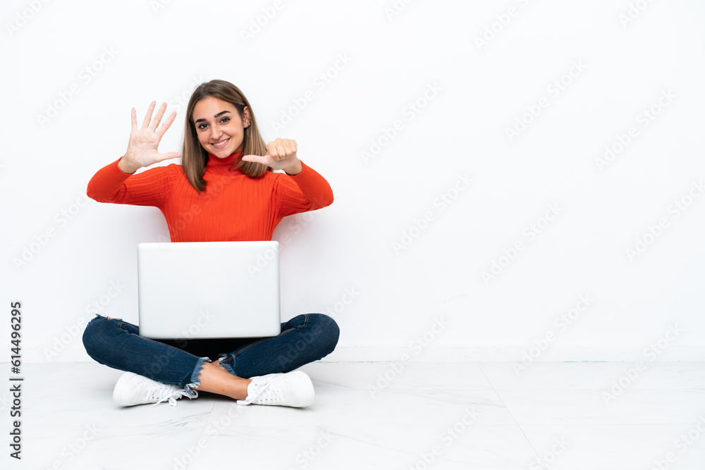Young caucasian woman sitting on the floor with a laptop counting six with fingers Young caucasian woman sitting on the floor with a laptop counting six with fingers