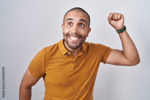Hispanic man with beard standing over white background dancing happy and cheerful, smiling moving casual and confident listening to music