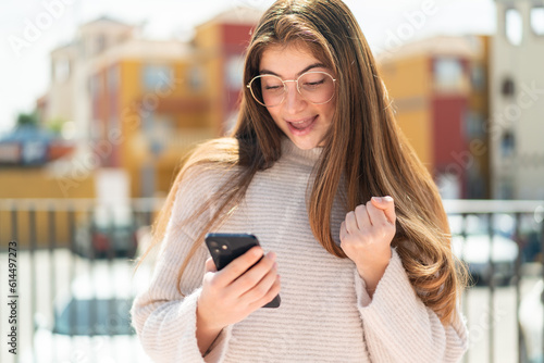Young pretty caucasian woman with glasses at outdoors surprised and sending a message