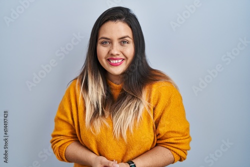 Young hispanic woman standing over isolated background with hands together and crossed fingers smiling relaxed and cheerful. success and optimistic