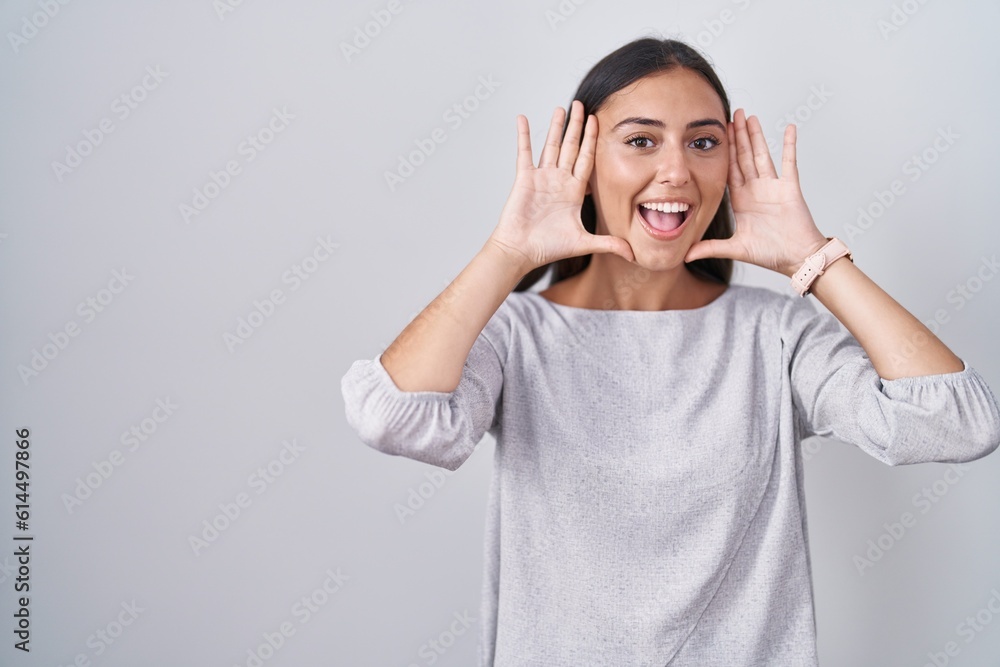 Young hispanic woman standing over white background smiling cheerful playing peek a boo with hands showing face. surprised and exited Young hispanic woman standing over white background smiling cheerful playing peek a boo with hands showing face. surprised and exited