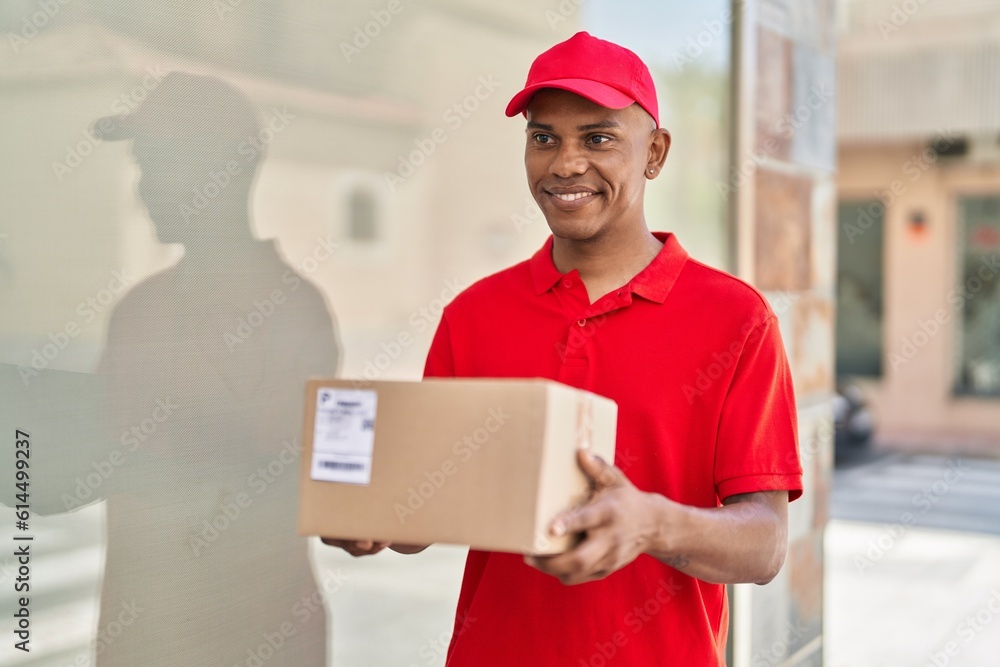Young latin man delivery worker holding package at street Young latin man delivery worker holding package at street