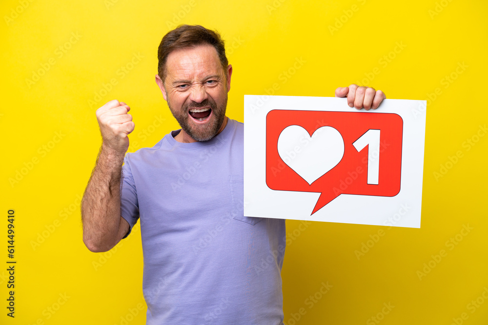 Middle age caucasian man isolated on yellow background holding a placard with Like icon and celebrating a victory Middle age caucasian man isolated on yellow background holding a placard with Like icon and celebrating a victory