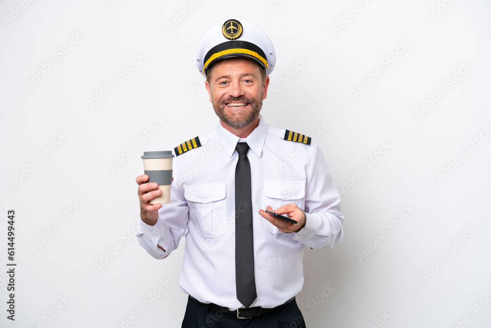 Airplane middle age pilot isolated on white background holding coffee to take away and a mobile Airplane middle age pilot isolated on white background holding coffee to take away and a mobile
