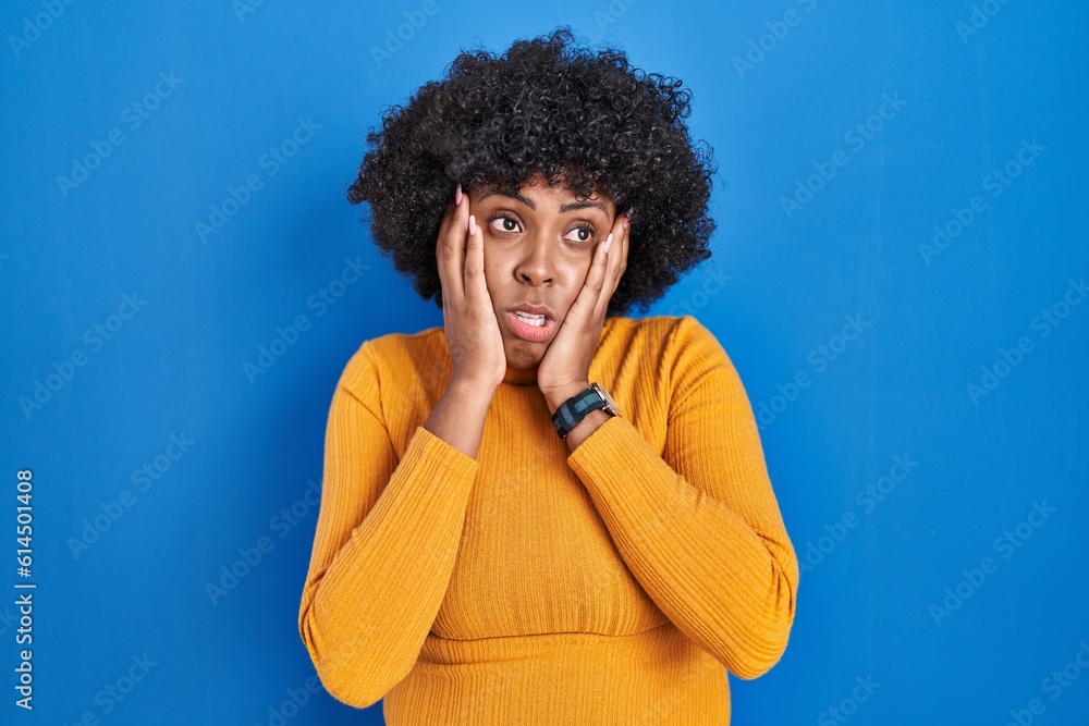 Φωτογραφία Black woman with curly hair standing over blue background tired hands covering f