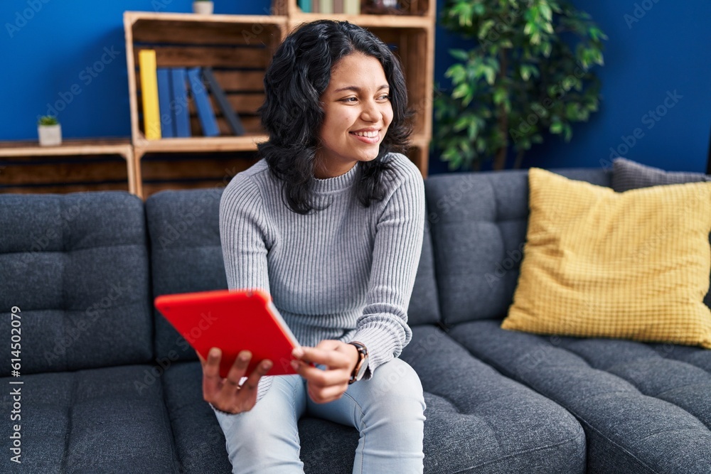 Young latin woman using touchpad sitting on sofa at home Young latin woman using touchpad sitting on sofa at home