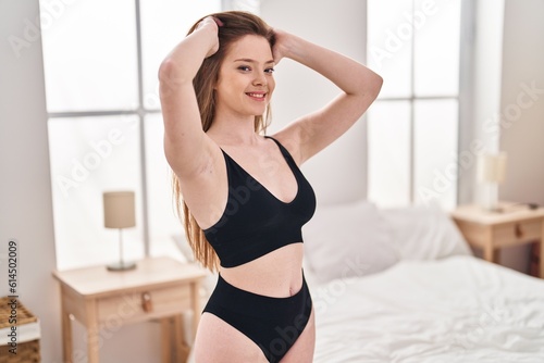 Young caucasian woman smiling confident combing hair with hands at bedroom